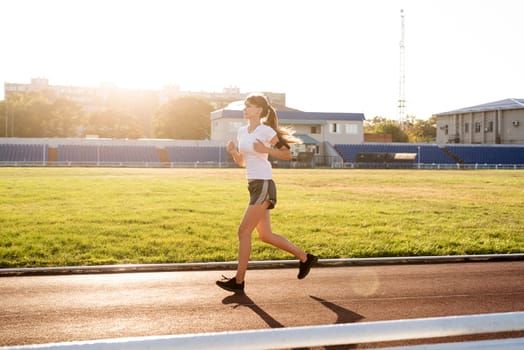 Healthy lifestyle concept. Active young woman jogging at the stadium