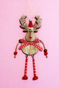 wooden deer with golden shiny antlers in santa hat on pink background.