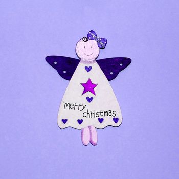 wooden angel with inscription on merry christmas dress on blue background.