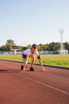 Sports and fitness. Teenager girl getting ready to run at stadium track