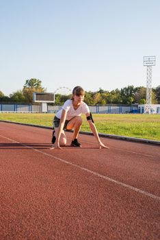 Sports and fitness. Teenager girl getting ready to run at stadium track