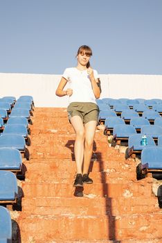 Active lifestyle. Teenager girl working out at the staduim running down the stairs