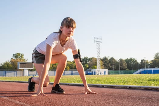 Sports and fitness. Teenager girl getting ready to run at stadium track