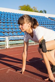 Sports and fitness. Teenager girl getting ready to run at stadium track