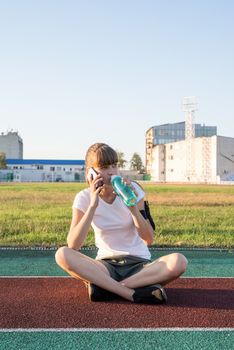 Active lifestyle. Teen girl making selfie at the stadium after workout drinking water