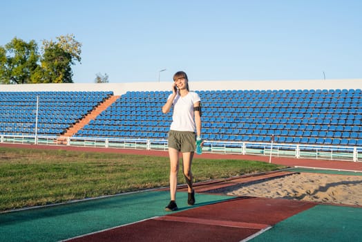 Sports and fitness. Teenager girl talking on the phone at the stadium