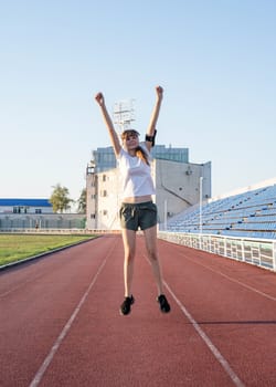 Teenager girl standing on the track rising her arms