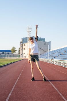 Teenager girl standing on the track rising her arms