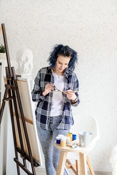 Creative woman artist putting oil paints on palette working in her studio