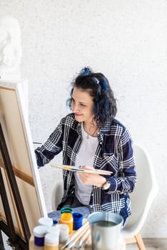 Creative woman artist painting a picture working in her studio