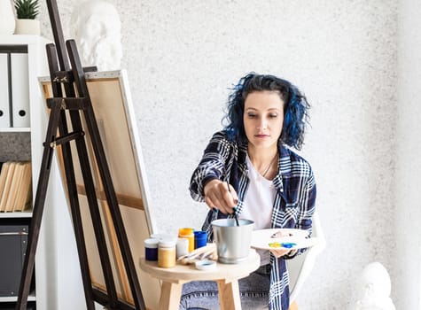 Creative woman artist painting a picture working in her studio