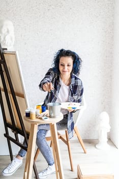 Creative woman artist painting a picture working in her studio