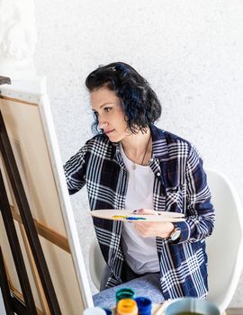 Creative woman artist painting a picture working in her studio