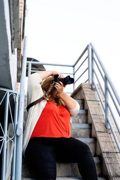 Travel, tourism and entertainment. Plus size woman photographer working at the street