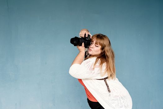 Travel, tourism and entertainment. Plus size woman photographer outdoors on blue solid background