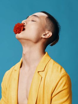 A handsome Asian man with a red flower in his mouth tilted his head back side view Copy Space close-up. High quality photo