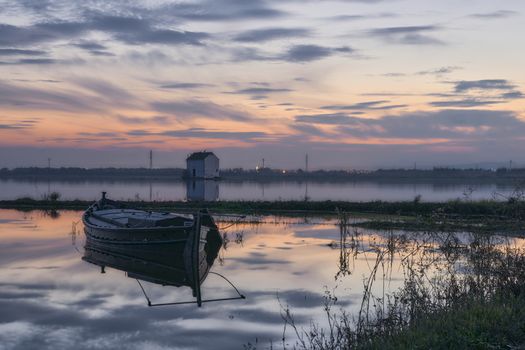 Small boat on the lake at sunset, houses, reflections, beautiful sky