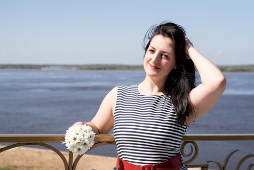 Young woman holding flowers on riverside background