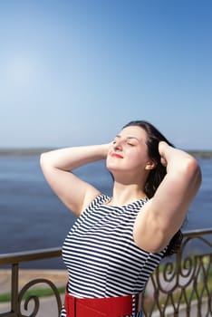 Happiness concept. beautiful young woman enjoying the sun standing by the river