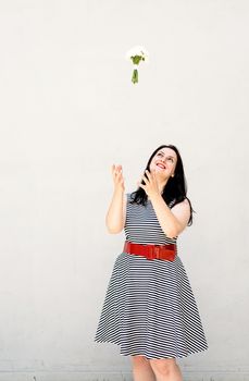 Happy young woman thowing a bouquet of flowers into the air on gray solid background