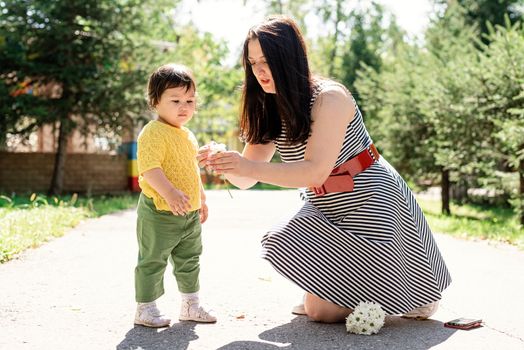 Multiethnic family. Mother walking her daughter in the park giving her flowers