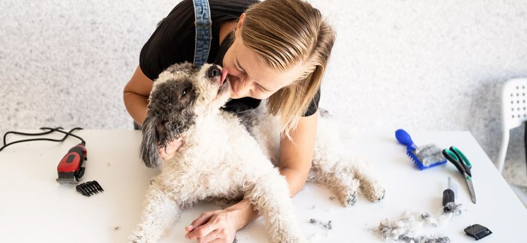 Pet care. Blong young groomer hugging and kissing her dog. Selective focus