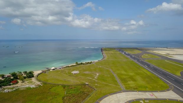 Runway at Denpasar International Airport in Bali, Indonesia. Runway reaching into the ocean. Aerial view to Ngurah Rai airport.