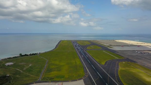 Runway at Denpasar International Airport in Bali, Indonesia. Runway reaching into the ocean. Aerial view to Ngurah Rai airport.