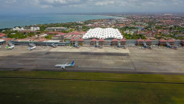 Denpasar International Airport Ngurah Rai, Bali Island, Indonesia. Aircrafts of national Indonesian air carrier in front of airport passenger terminal.