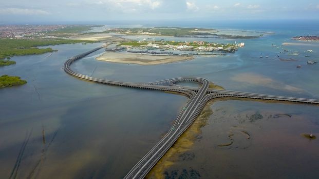 Aerial view of Bali Mandara toll road over sea. Car, motorbike bridge across the Gulf of Benoa connecting Denpasar city and South Kuta, Nusa Dua and Ngurah Rai International Airport.