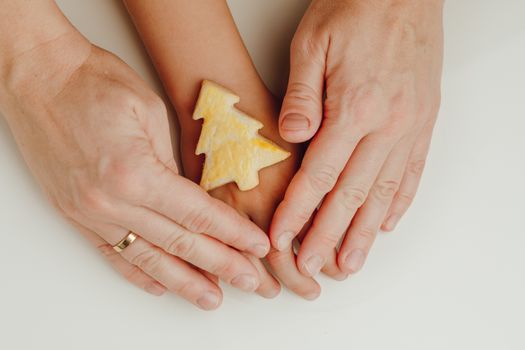 mother and child holding a Christmas tree cookie in hands