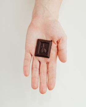 woman holding a piece of dark chocolate bar in hand