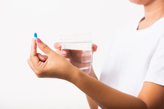 Closeup young Asian woman hold pill drugs in hand ready take medicines with a glass of water, studio shot isolated on white background, Healthcare and medical pharmacy concept