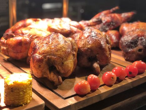 Roasted chicken with tomato and corn on wooden table