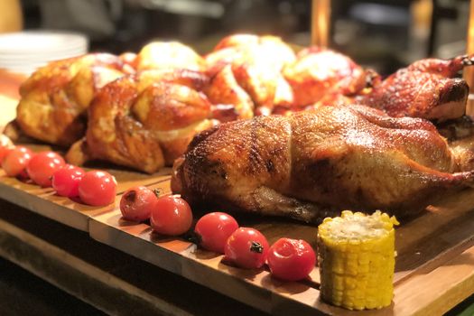 Roasted chicken with tomato and corn on wooden table