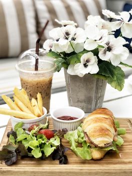 Smoked salmon croissant sandwich served with coffee and french fried