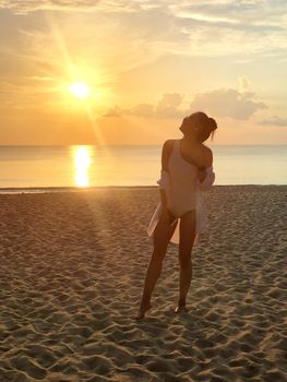 Happiness woman on beach. She is enjoying serene ocean nature sunset during travel holidays vacation outdoors. at phuket Thailand