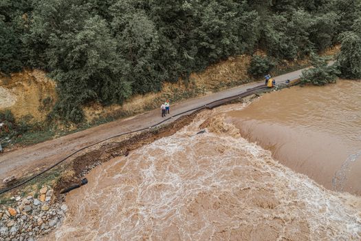 After big rain a river that overflows threatens the road, bridge and property