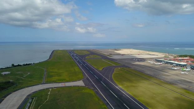 Runway at Denpasar International Airport in Bali, Indonesia. Runway reaching into the ocean. Aerial view to Ngurah Rai airport.