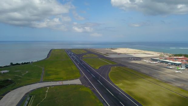 Runway at Denpasar International Airport in Bali, Indonesia. Runway reaching into the ocean. Aerial view to Ngurah Rai airport.