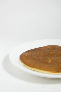 Freshly baked pancake on a plate on a white background