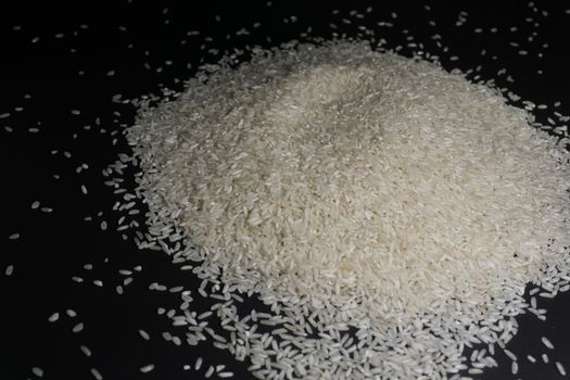 Scattered white uncooked rice on a black background