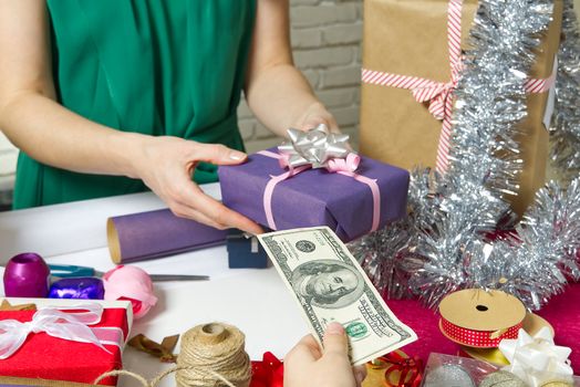 Paying for Gift Wrap at wrapping and packing service table with USA dollars banknotes.