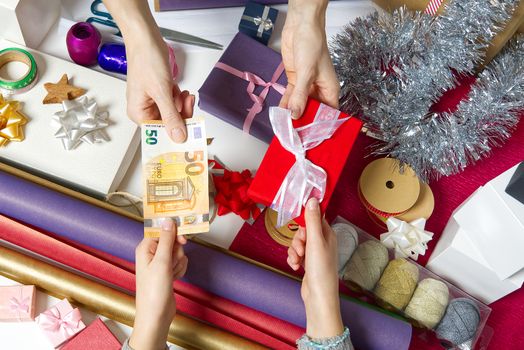 Paying for Gift Wrap at wrapping and packing service table with Euro banknotes.