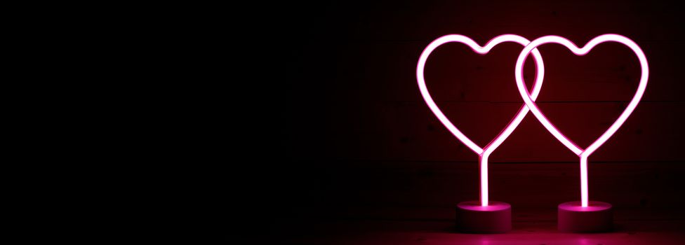 Two glowing pink neon hearts Valentines day party concept