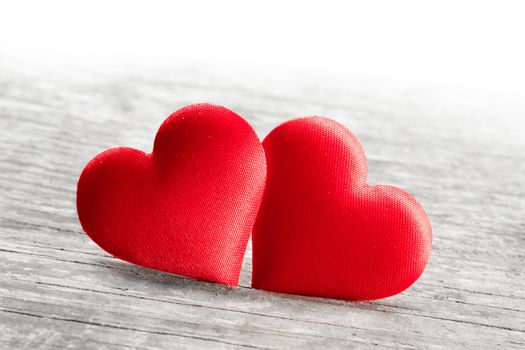 Valentine's day two red silk hearts on wooden background, love concept