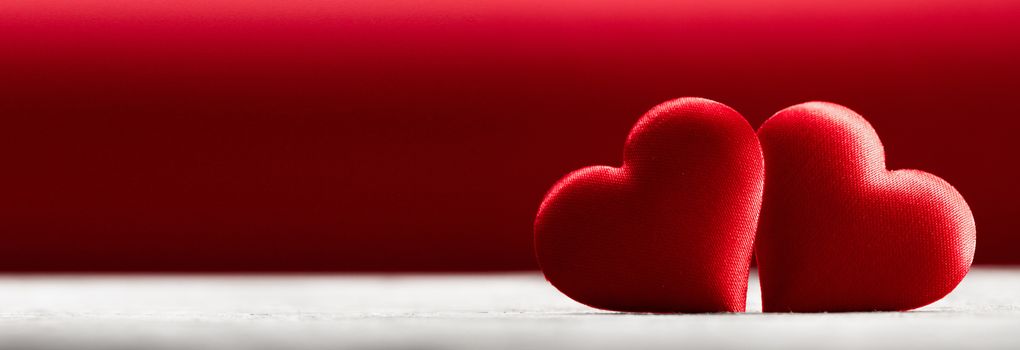 Valentine's day two red silk hearts on wooden background, love concept