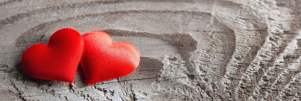 Valentine's day two red silk hearts on wooden background, love concept