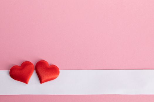 Valentine's day two red silk hearts and white paper on pink paper background, love concept