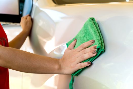 Women are wiping the car with green textile